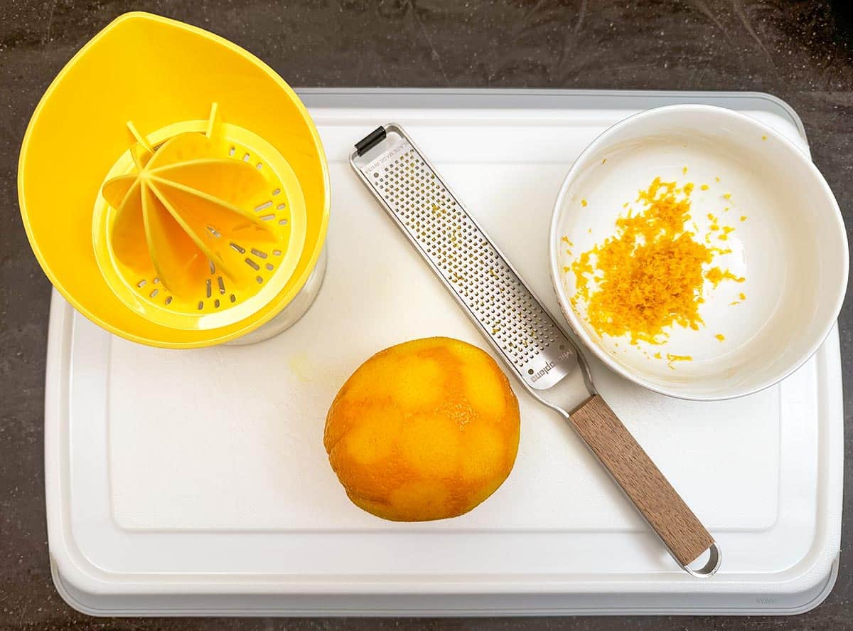 Zesting and juicing an orange on a cutting board,