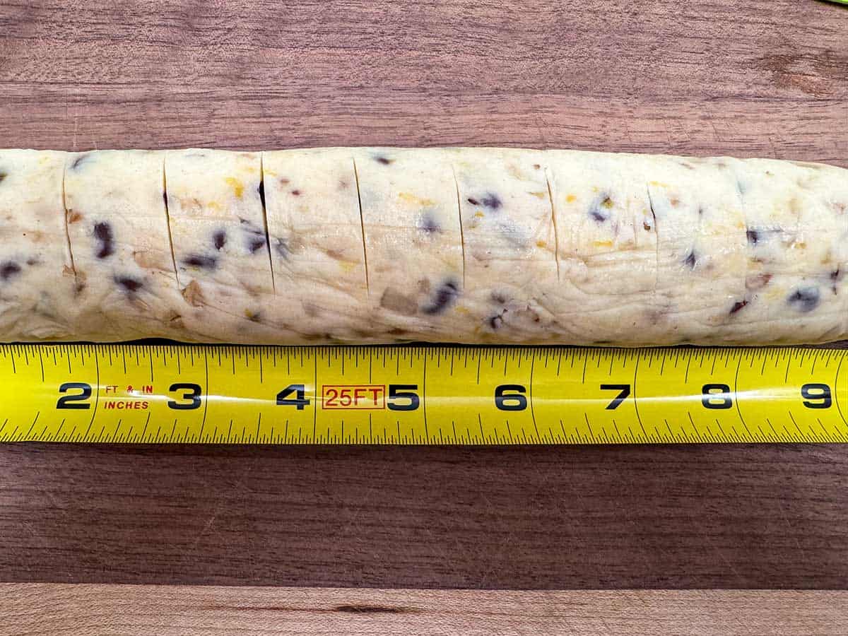 Using a measuring tape to make even scores on the cookie log.