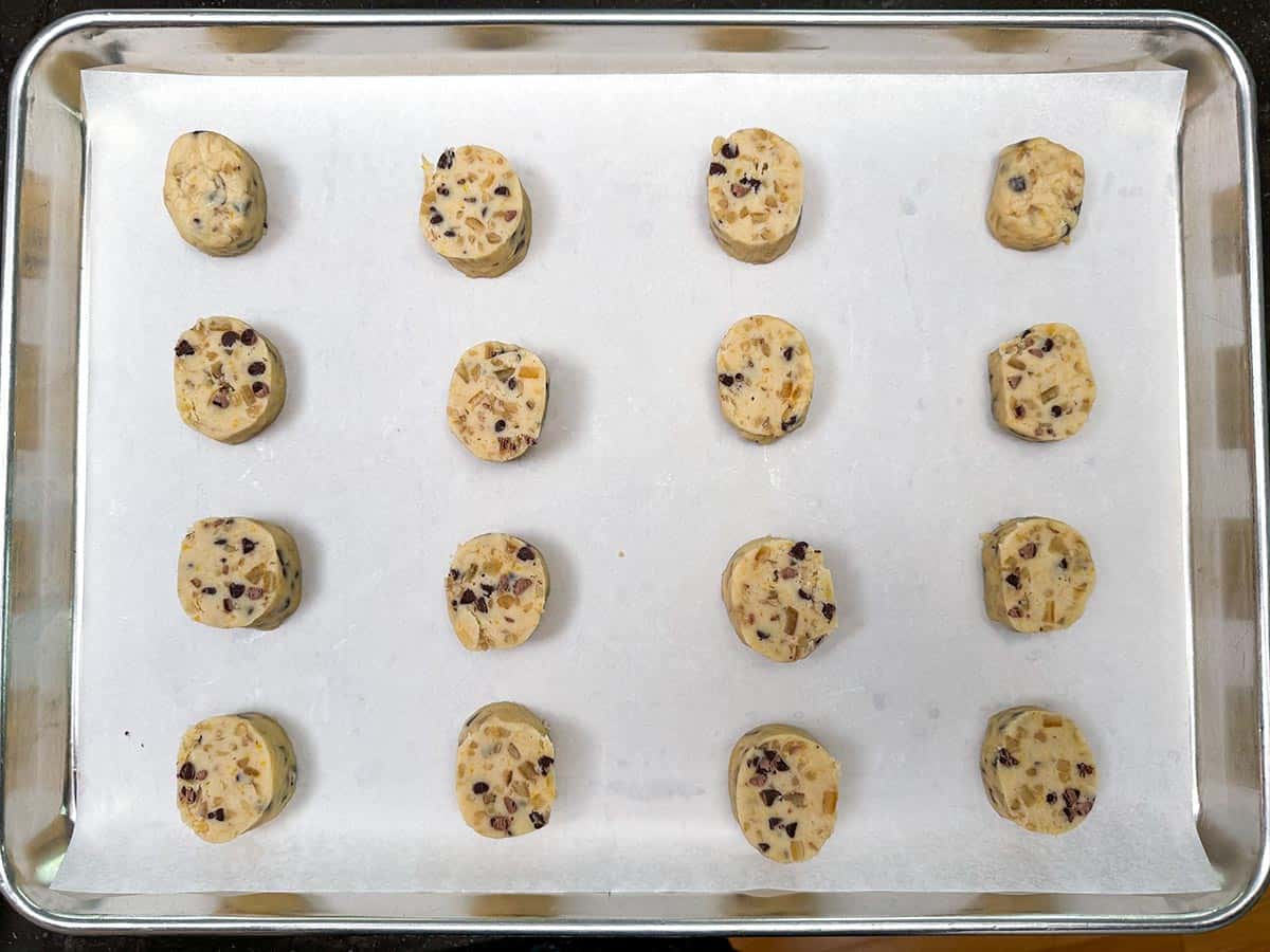 One log sliced into cookies and added to a sheet pan for baking.