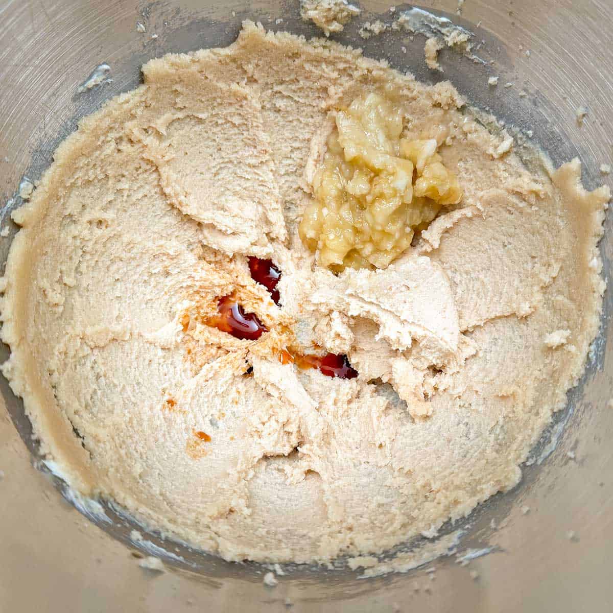 Adding mashed banana and vanilla extract to the butter-sugar mixture.