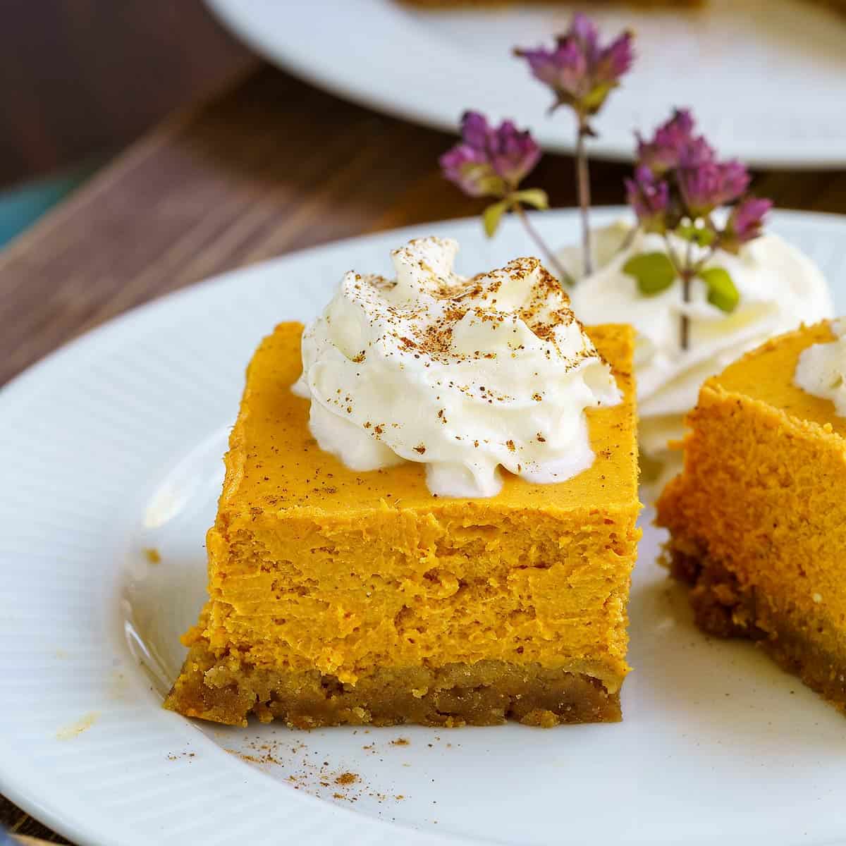 Pumpkin cheesecake bites on a plate. Also whip cream on top. 