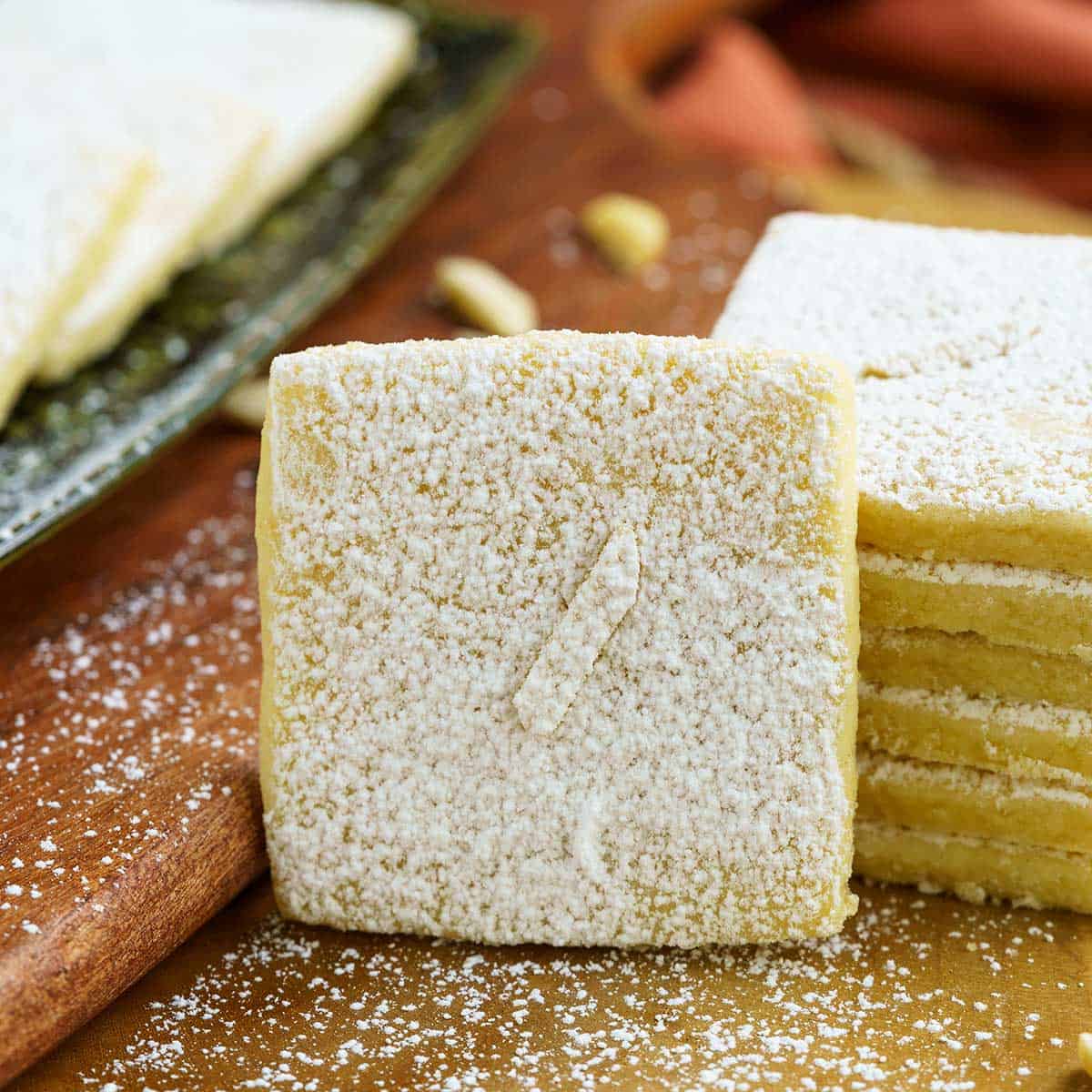 Square cookie with powdered sugar on a wooden board.