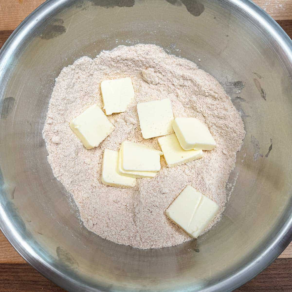 Adding cubed butter to a bowl with the flour and brown sugar to make the crumble.