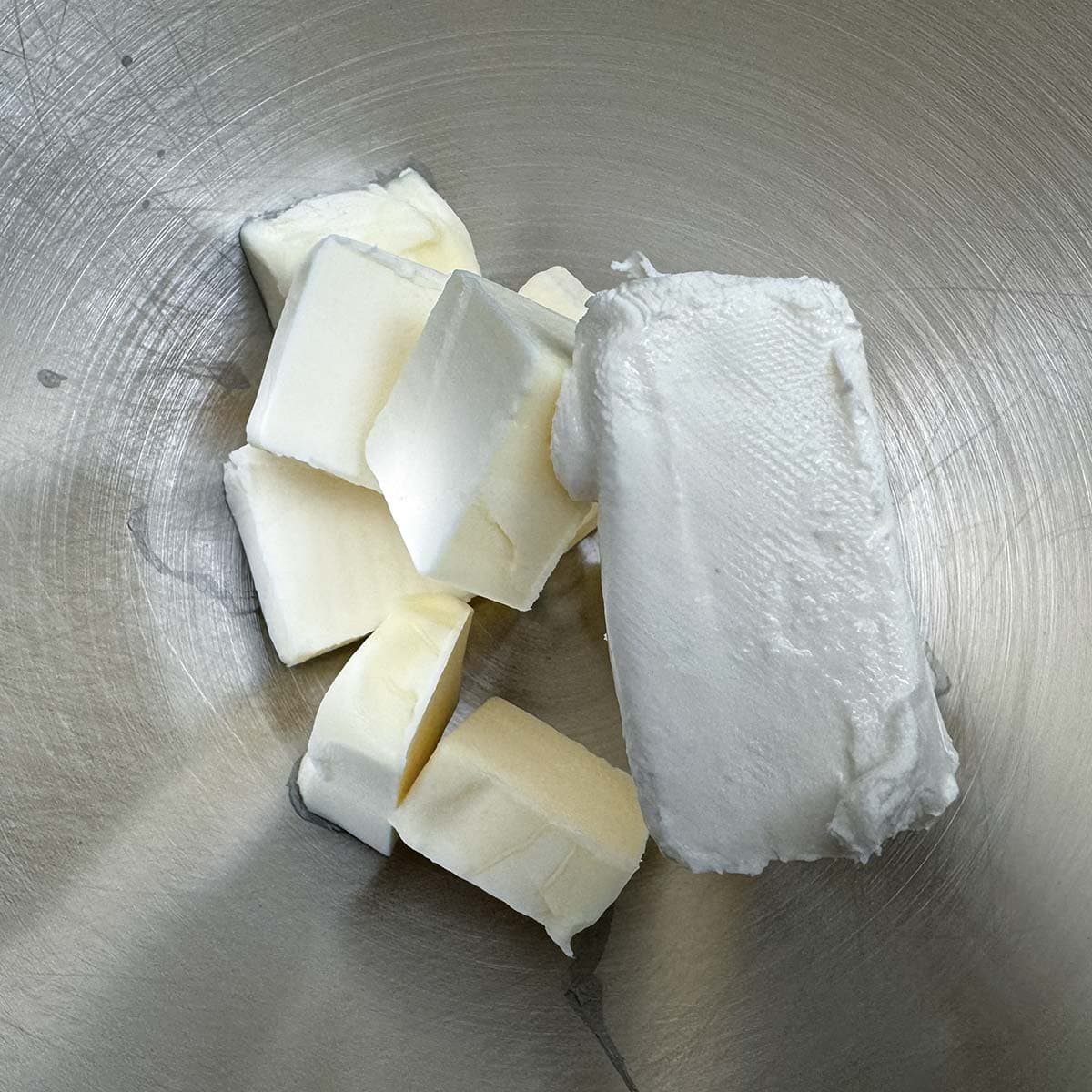 Cubed butter and half a block of cream cheese in a mixer bowl.