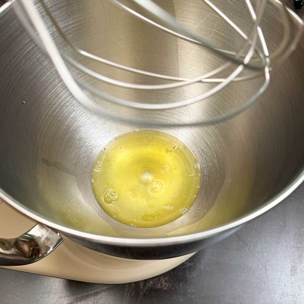 Adding 3 egg whites to a mixer bowl before beating them.