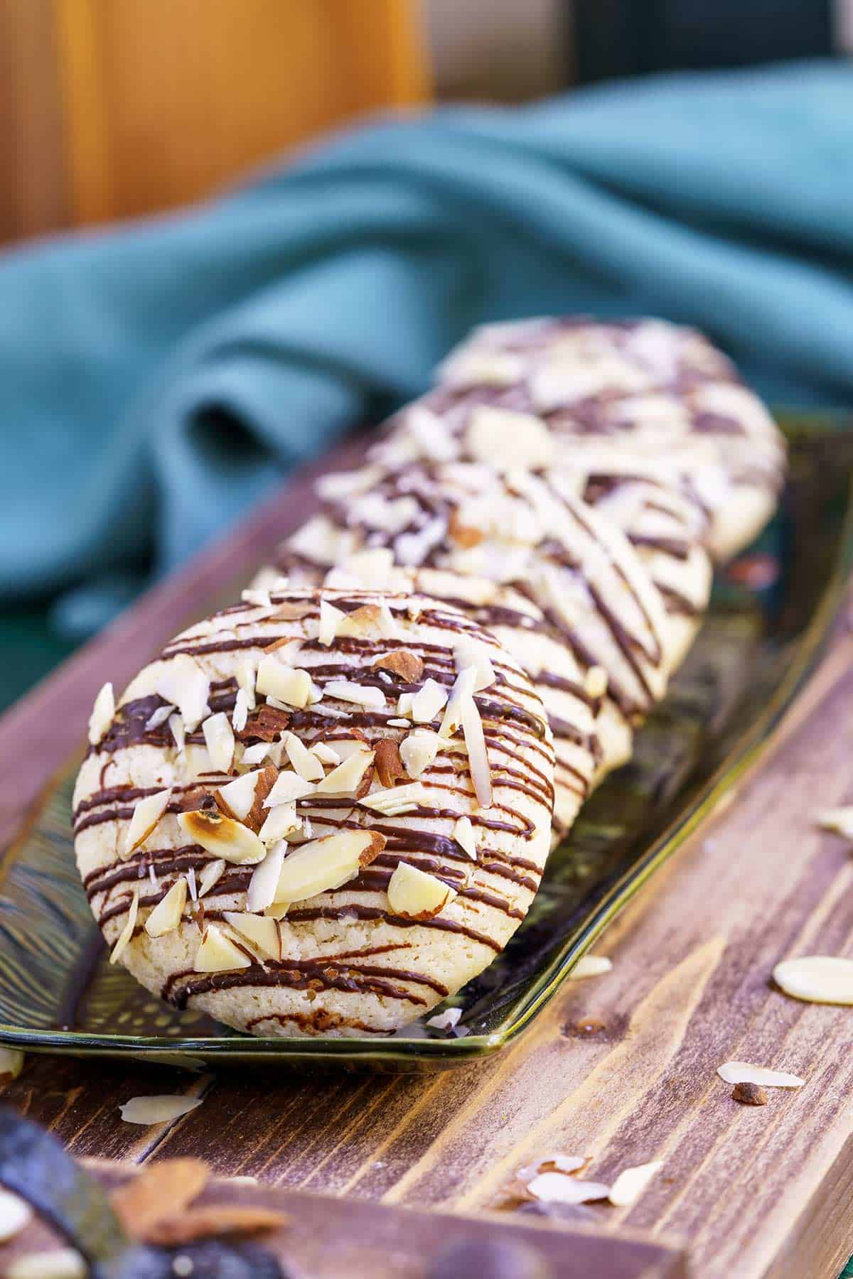 Italian almond cookies with bittersweet chocolate on a long narrow plate.