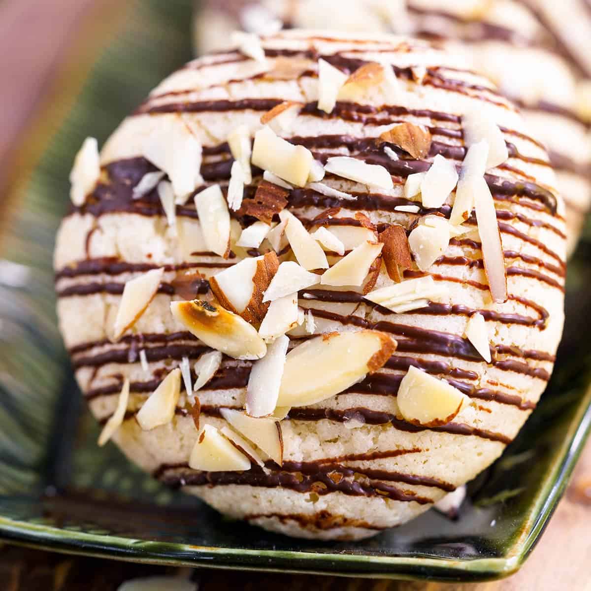 Cookie with chocolate drizzle and almond pieces on top. 