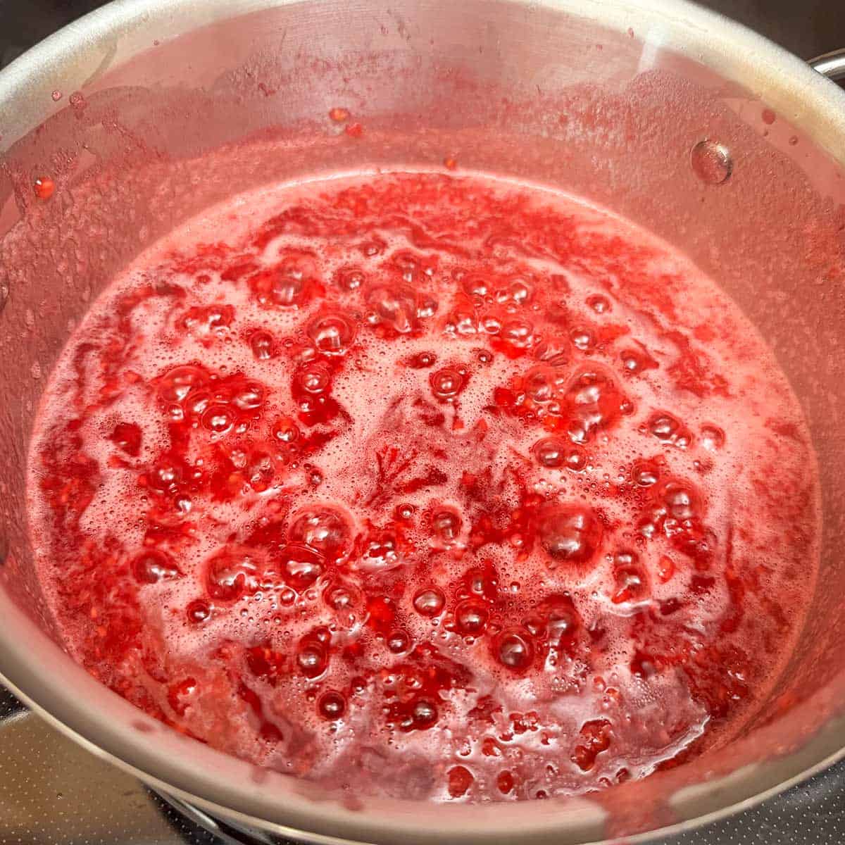 The raspberry filling on a low boil in the saucepan.