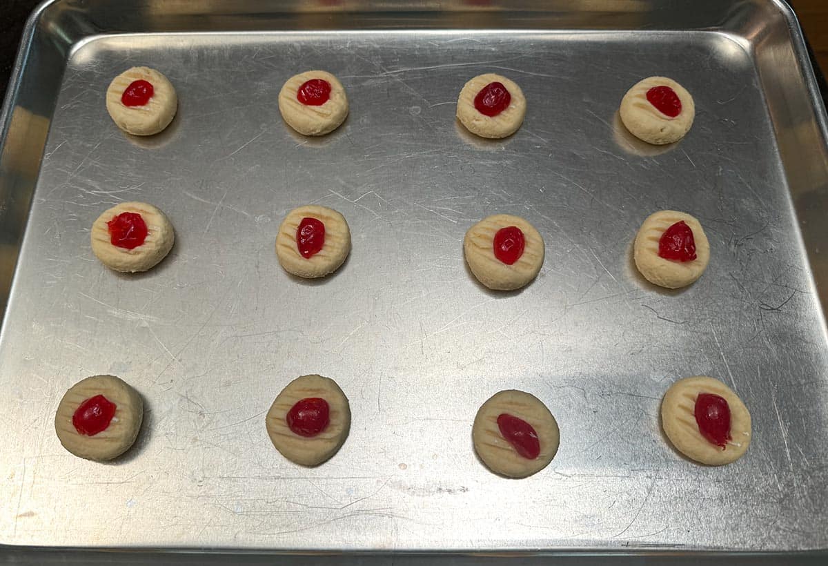 Added half cherries on top of the prebaked cookies sitting on a sheet pan.