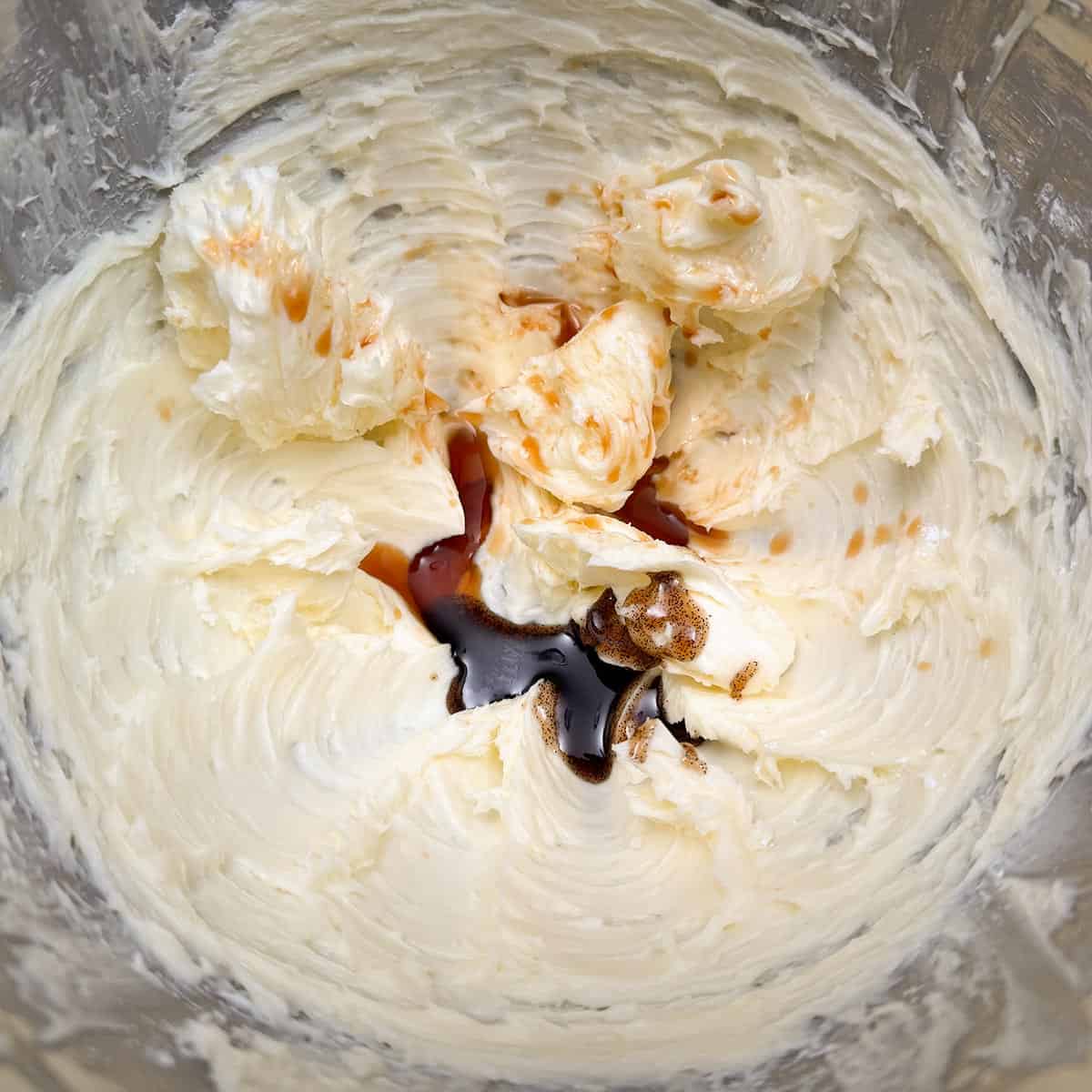 Adding vanilla bean paste and vanilla extract to the butter-sugar mixture.