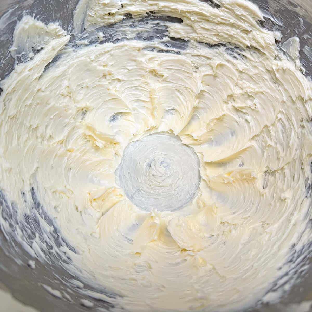 Creamed butter in a mixer bowl with soft peaks.