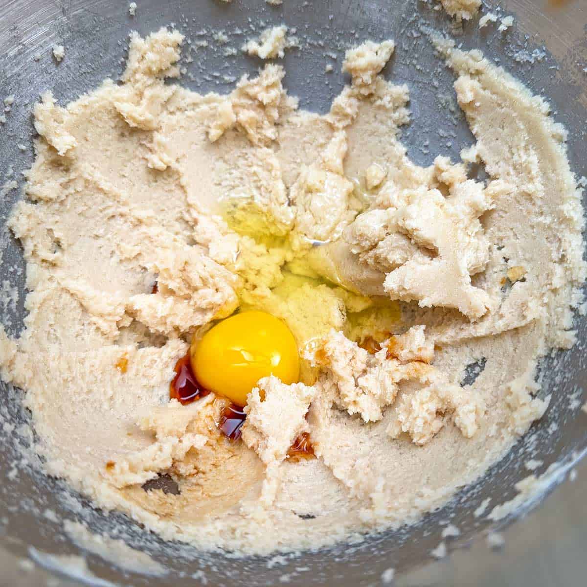 Adding an egg and vanilla extract to butter-sugar mixture.