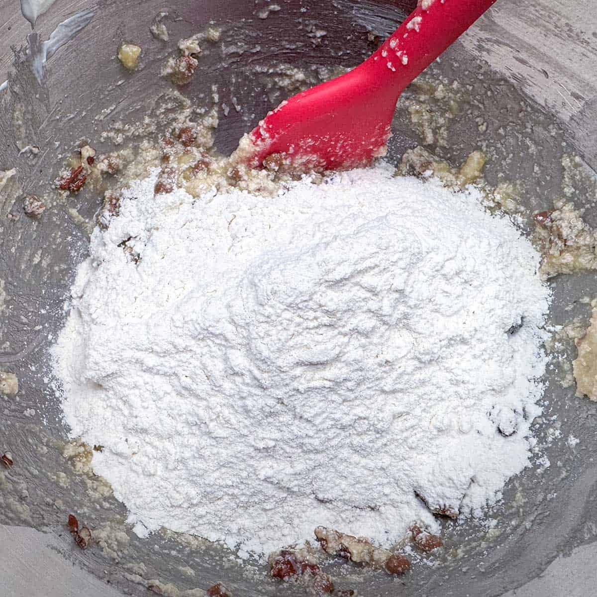 Folding the flour into the wet cookie dough with a spatula.