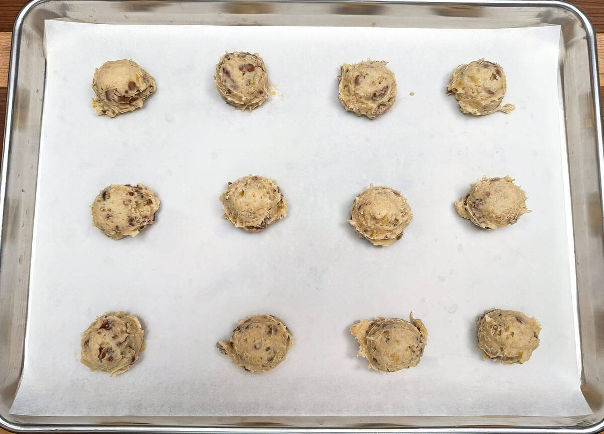 Scooped cookie dough on a parchment-lined sheet pan.