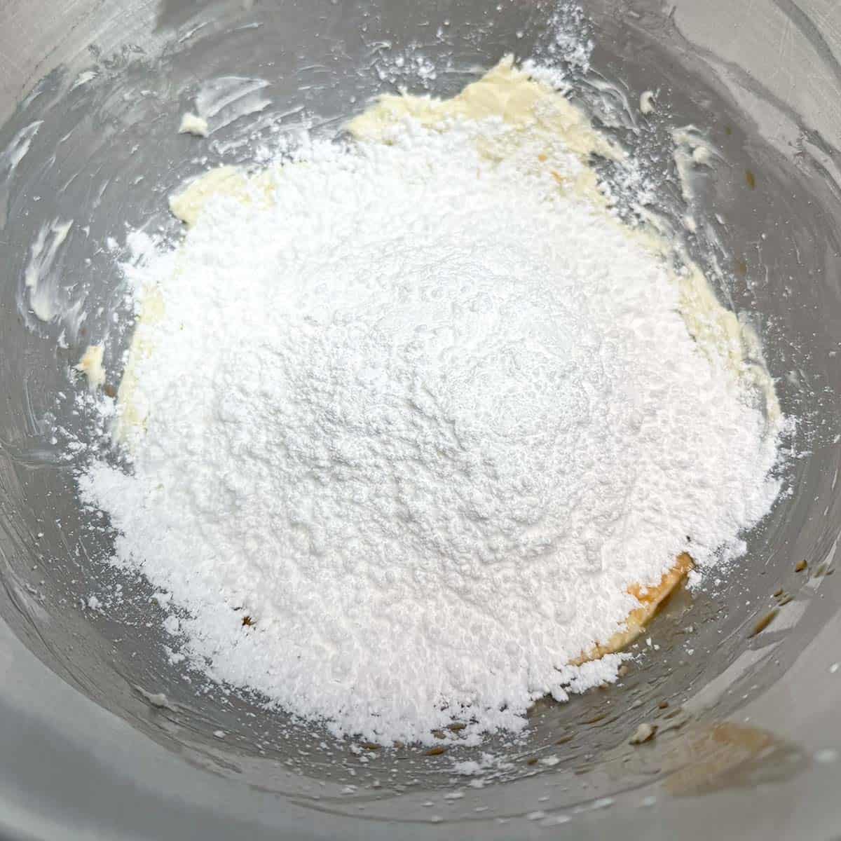 Adding the powdered sugar to the creamed butter for the frosting.