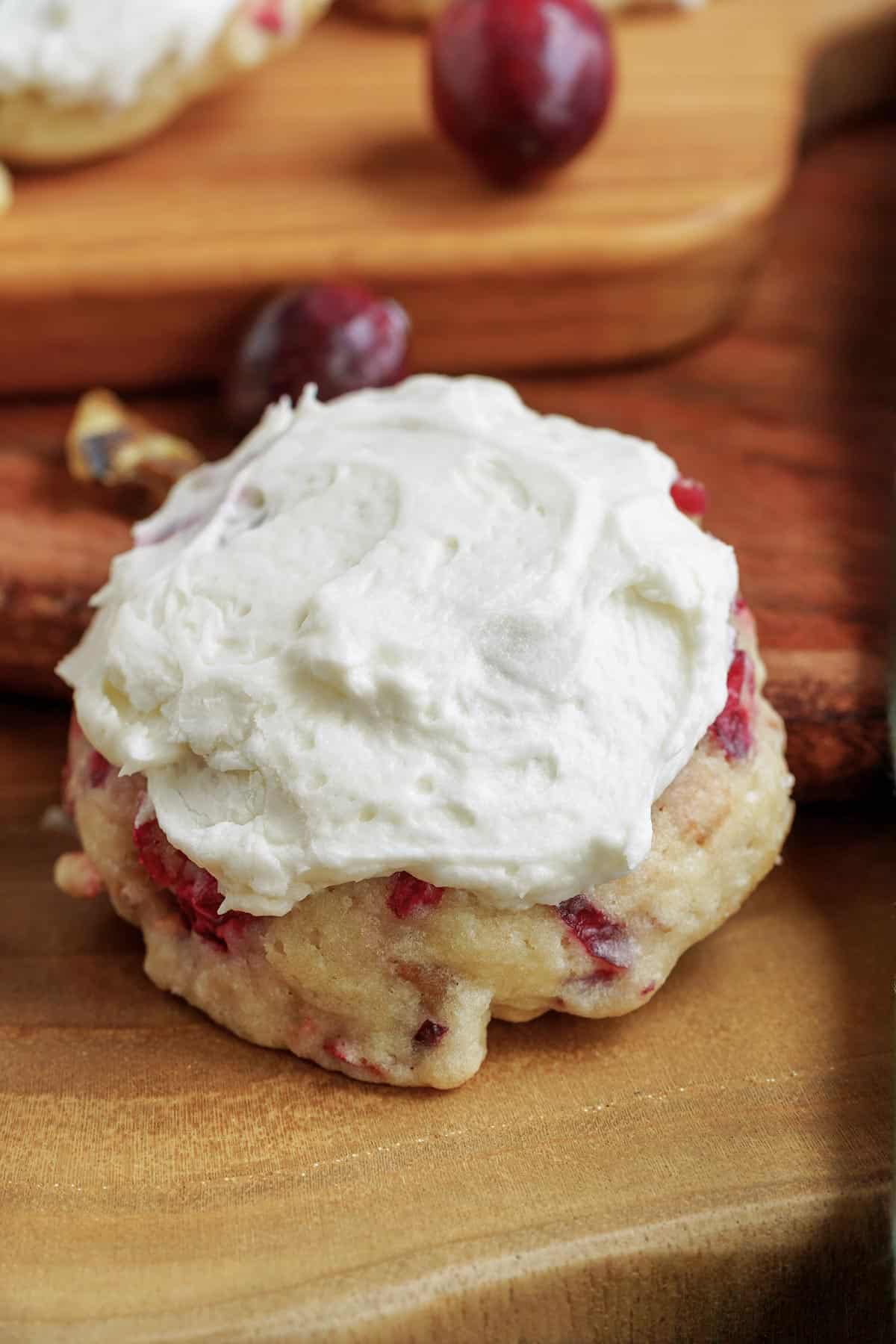 A fresh cranberry and walnut frosted cookies with cranberries and walnut scattered around.