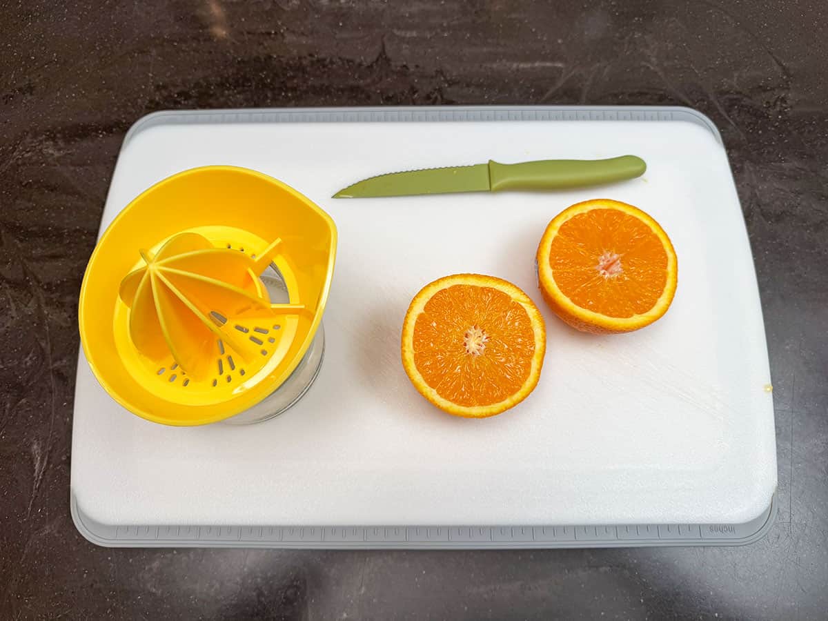 Juicing an orange on a cutting board.