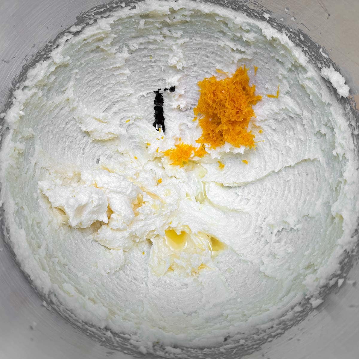 Adding orange juice and zest along with the almond extract to the butter-sugar mix.