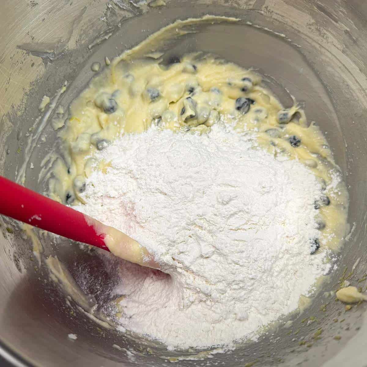 Using a spatula to mix the flour mixture to the soft cookie dough.