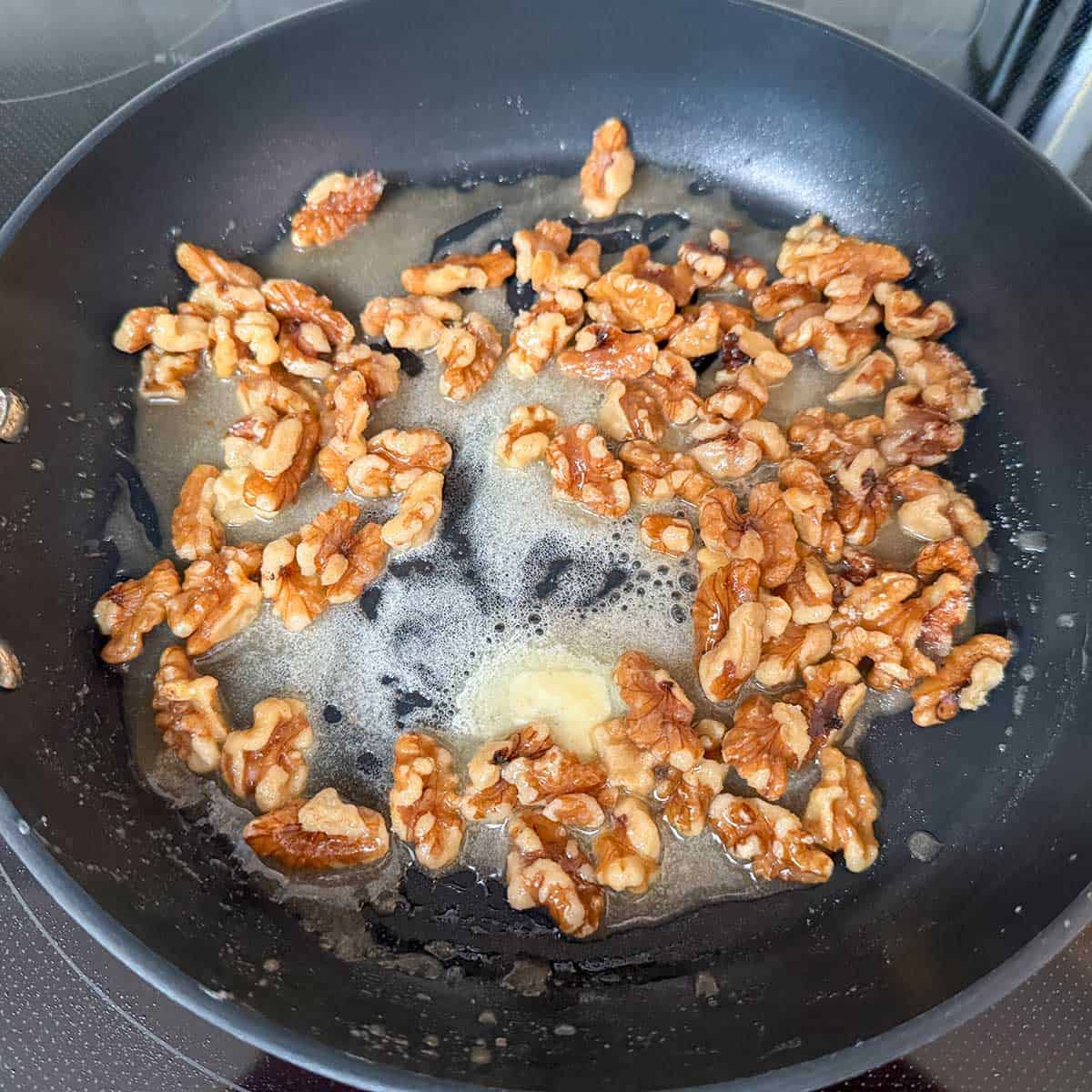 In a non-stick pan the butter sugar and maple syrup melting so it will cover the walnut halves.