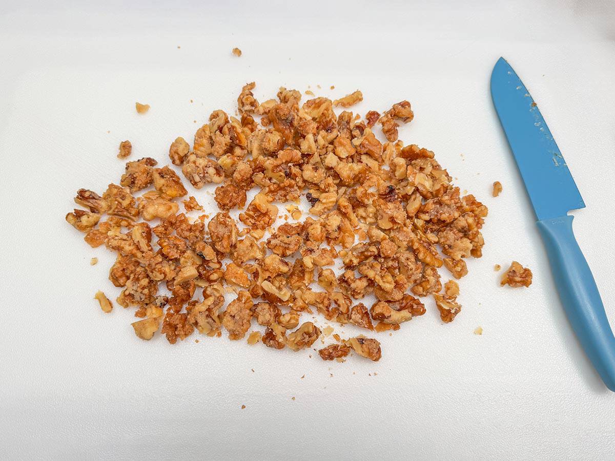 Chopping the glazed maple walnuts on a cutting board and sharp knife.