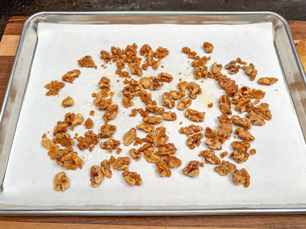 Glazed maple walnuts going from the fry pan to the parchments lined sheet pan to cool.