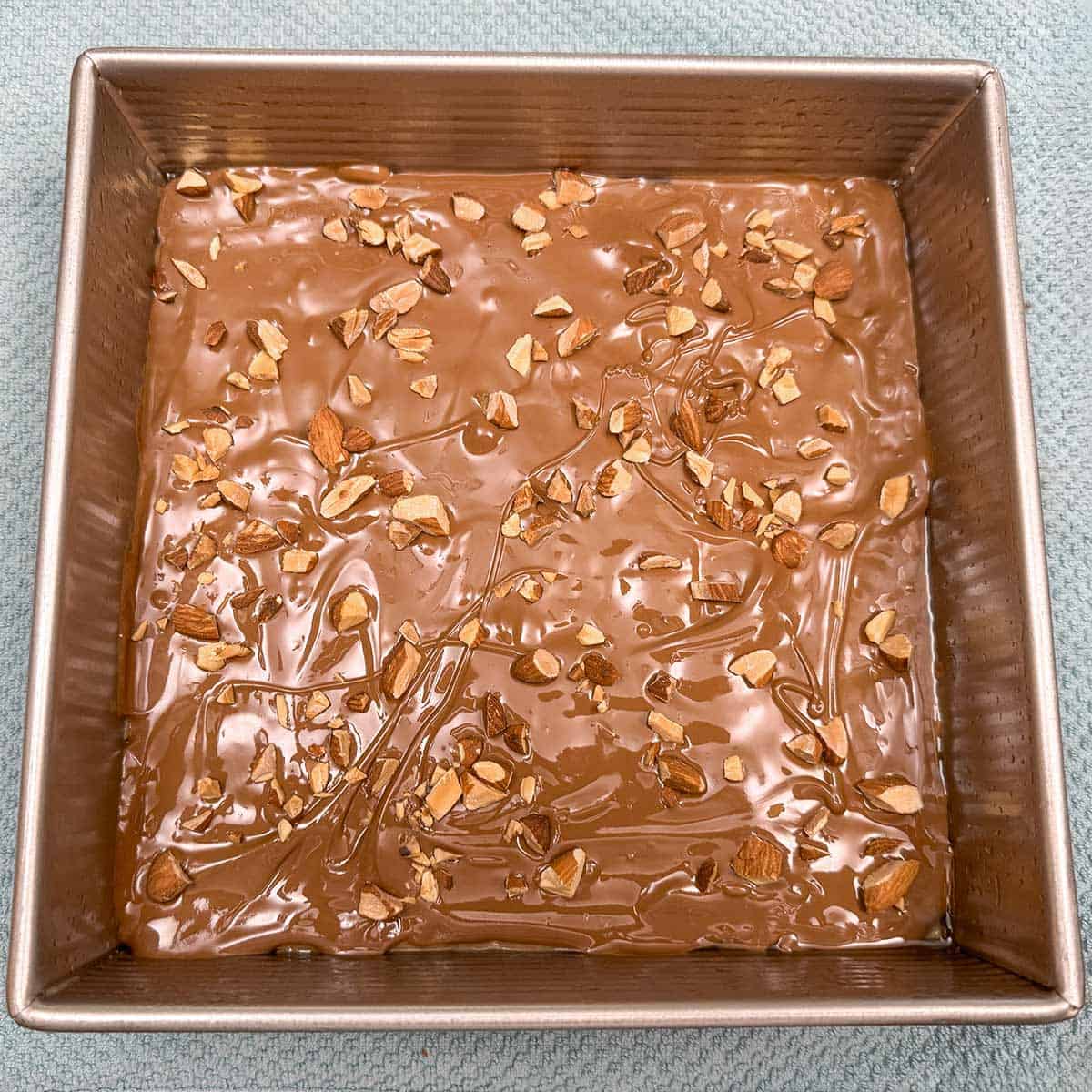 Melted chocolate and almonds on top in a pan and ready to set overnight.