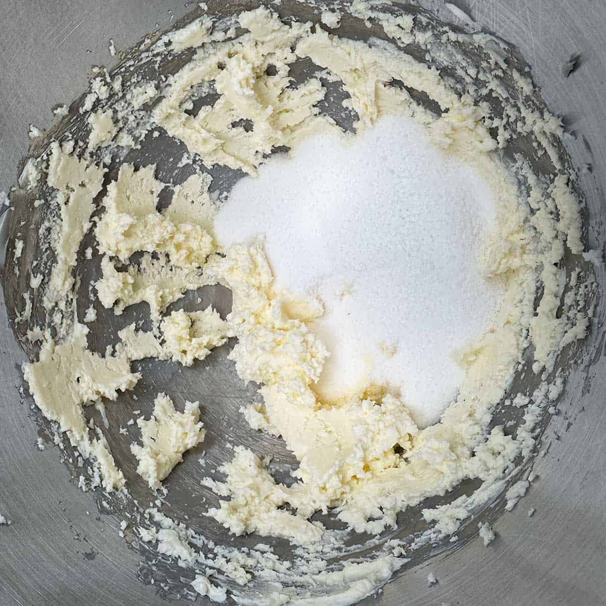 Mixed cream cheese and butter with the sugar being added to be mixed in.