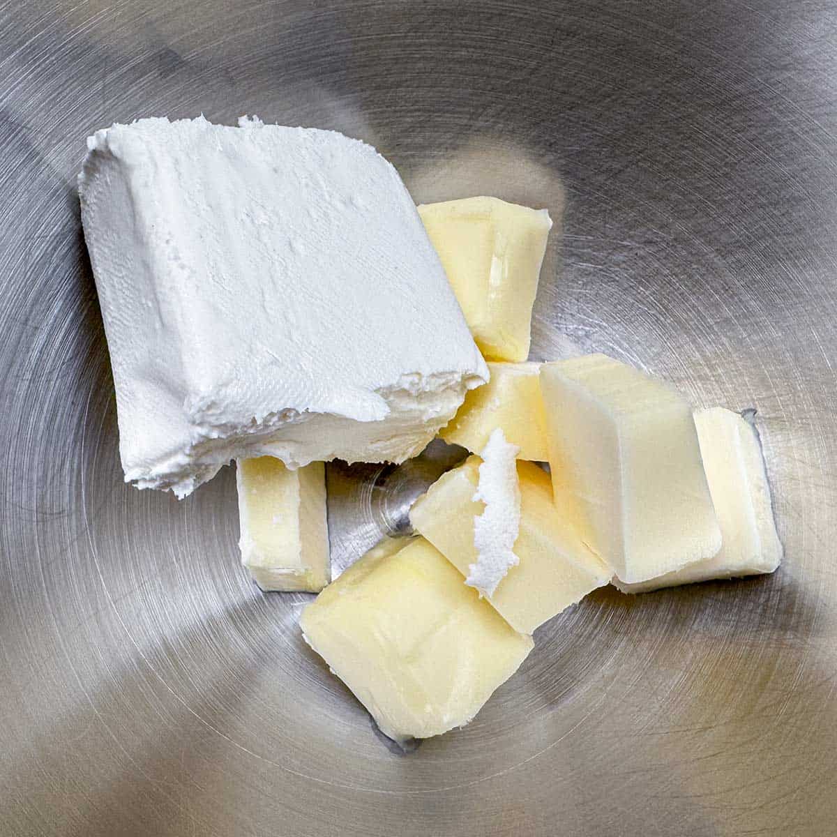 Cubed butter and cream cheese in a mixer bowl.
