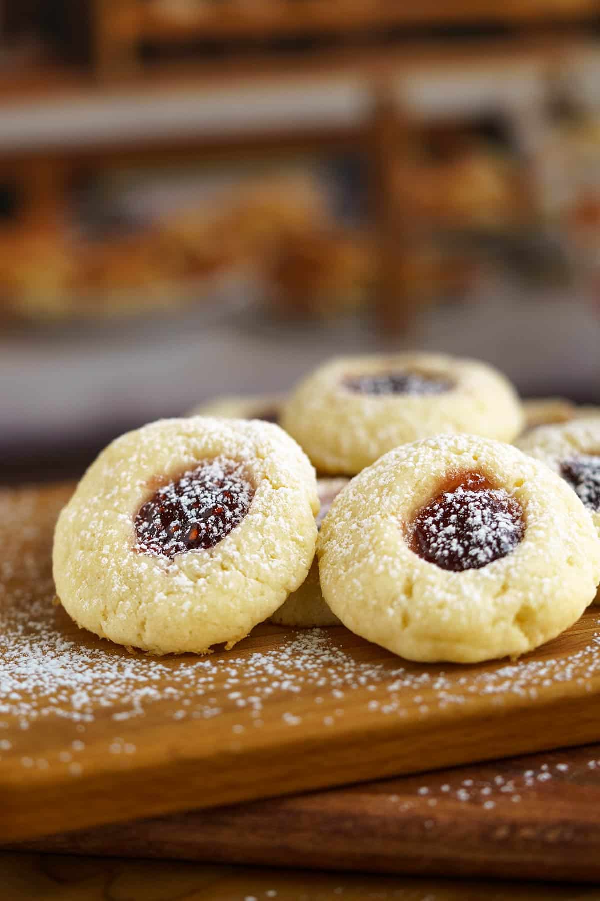 A group of Raspberry Cream Cheese Cookies on a wooden board with powdered sugar sprinkled on top of the cookies.