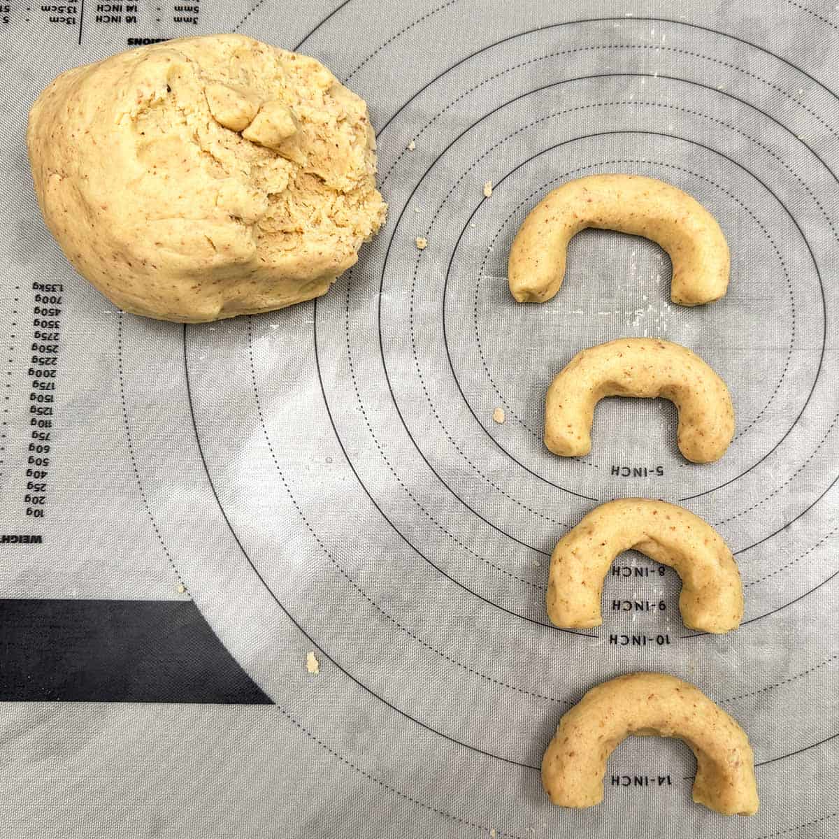 Take a ball of cookie dough off the large ball and roll and shape the dough into a crescent shape.