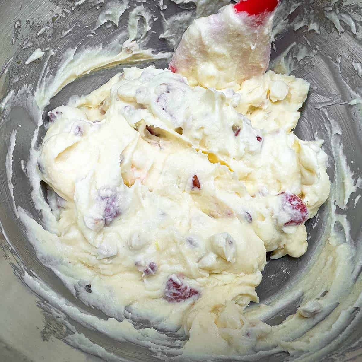 Adding oven-dried raspberries using a spatula.