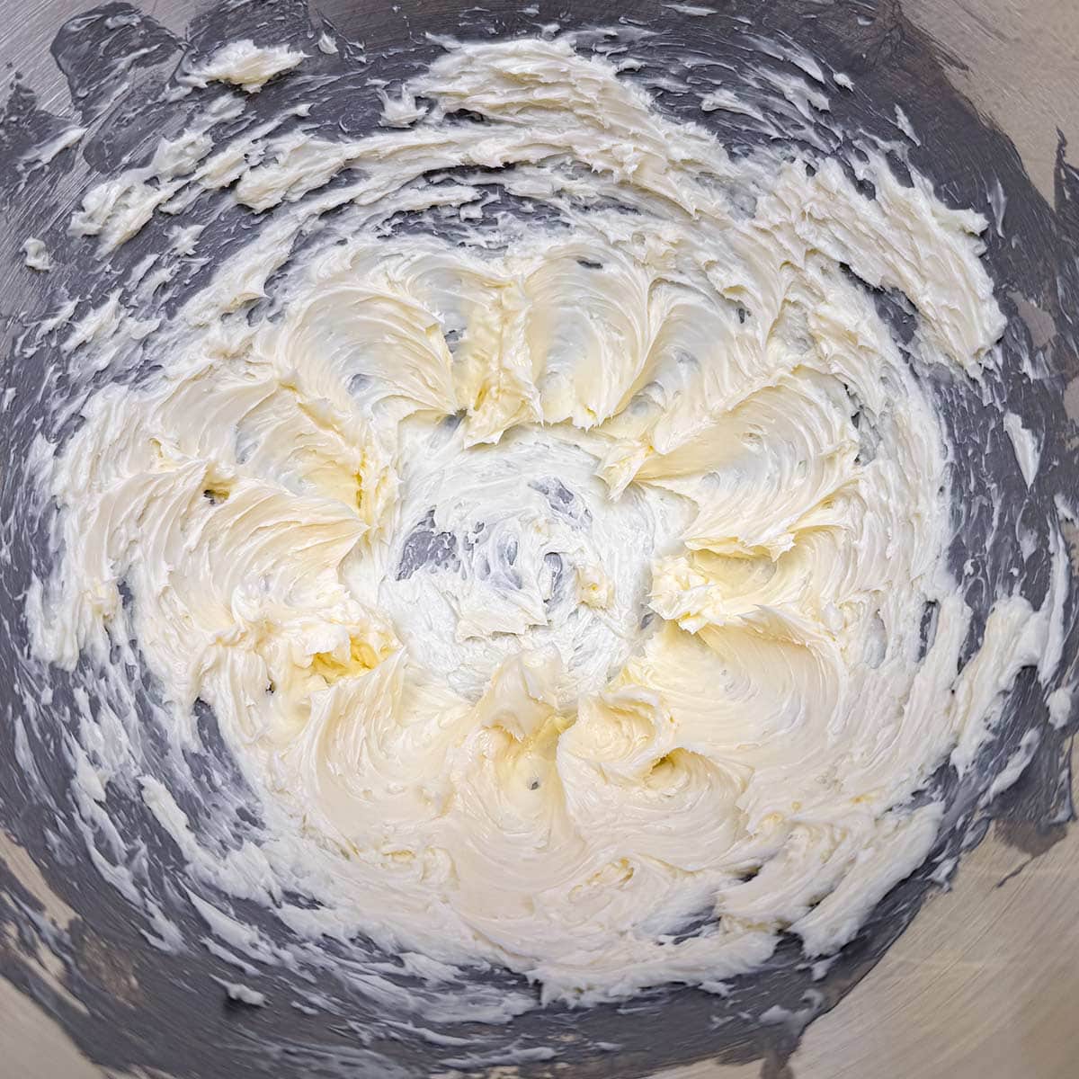 Creamed butter in a mixer bowl with soft peaks.