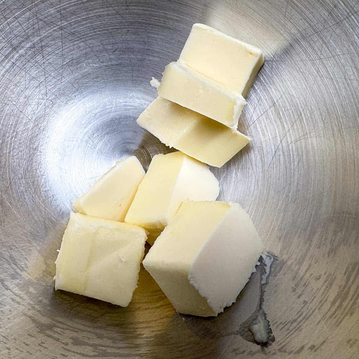 Room temperature butter cubed in a mixer bowl.