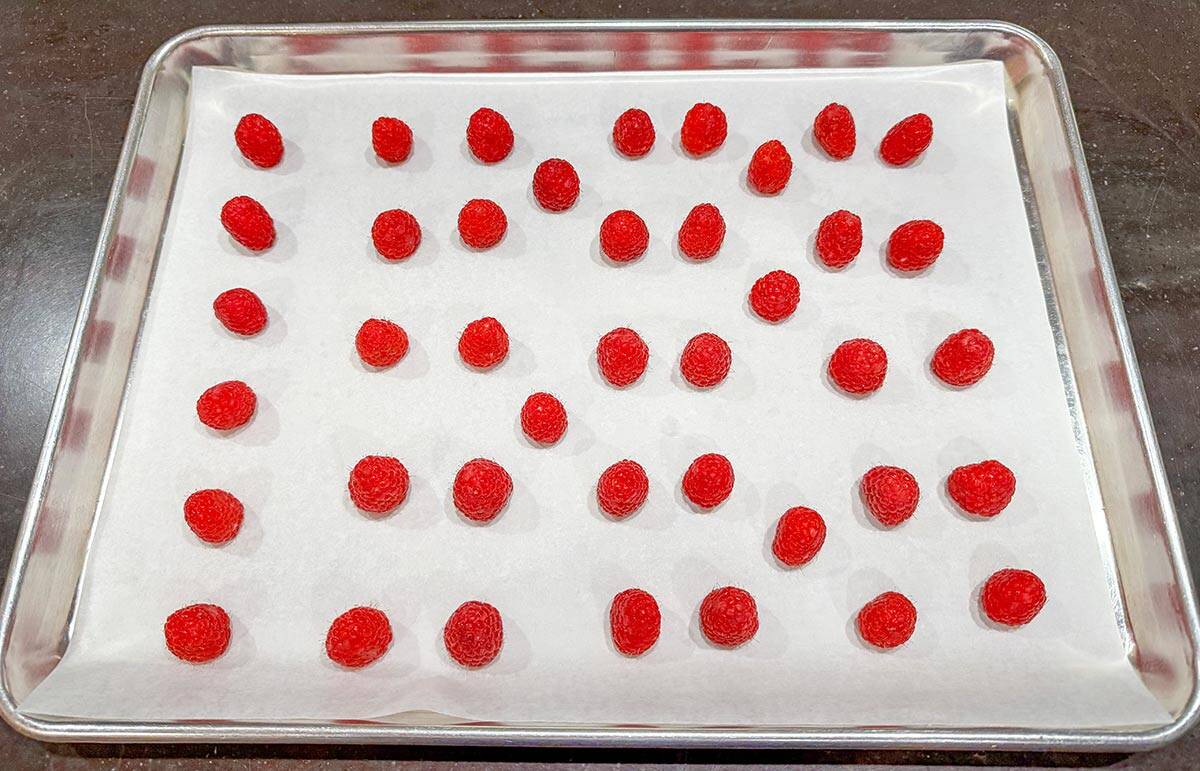 Standing the clean raspberries on a parchment lined sheet pan to be oven dried.