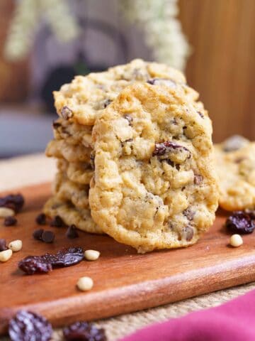 A stack of baked cookies with one standing up to front view on a wooden board.