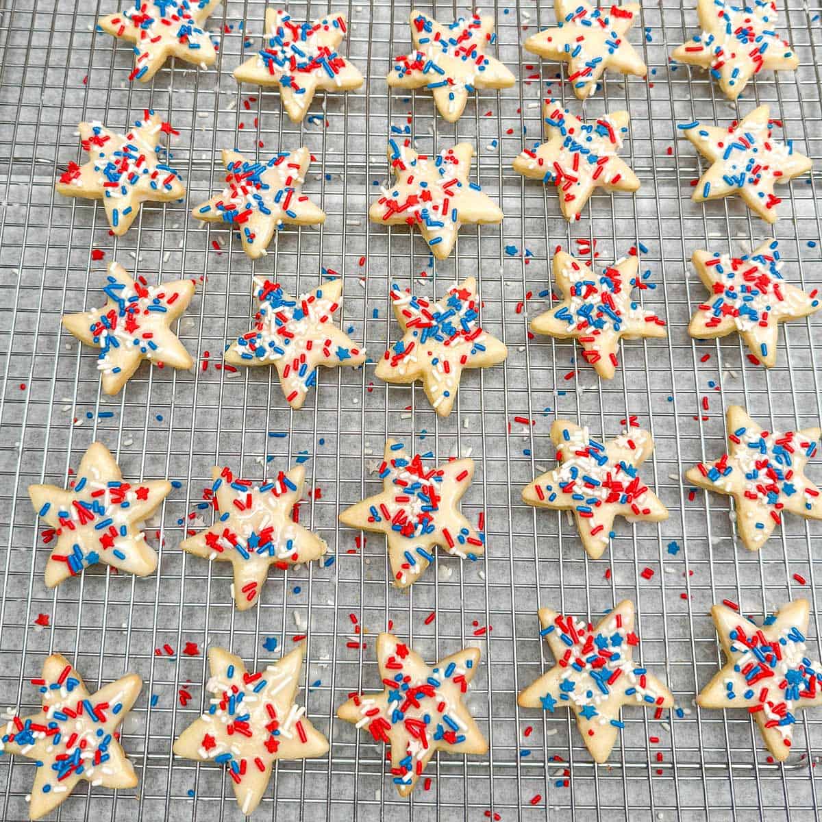 Honey almond glazed cookies with colorful jimmies on top drying on a rack.