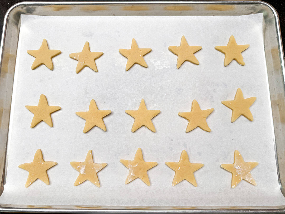 Cutout stars on a parchment lined cookie sheet pan.