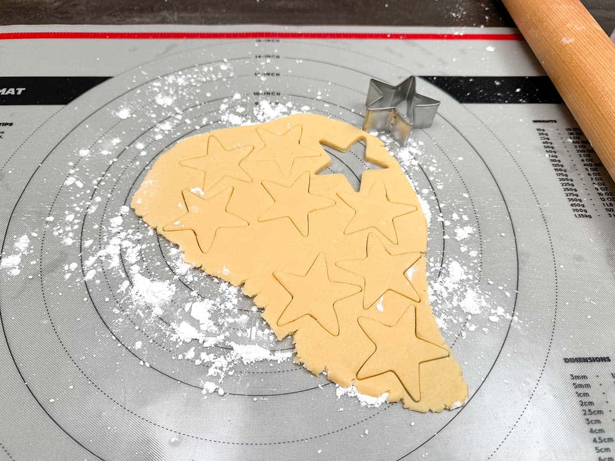 Using a star cookie cutter to get as many cookies as you can on half a disk of cookie dough.