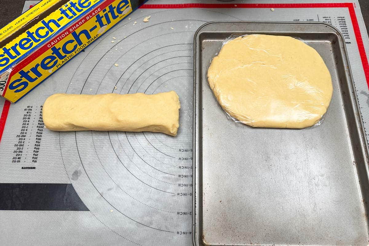 Kneaded cookie dough cut in half, flattened and wrapped in plastic wrap.