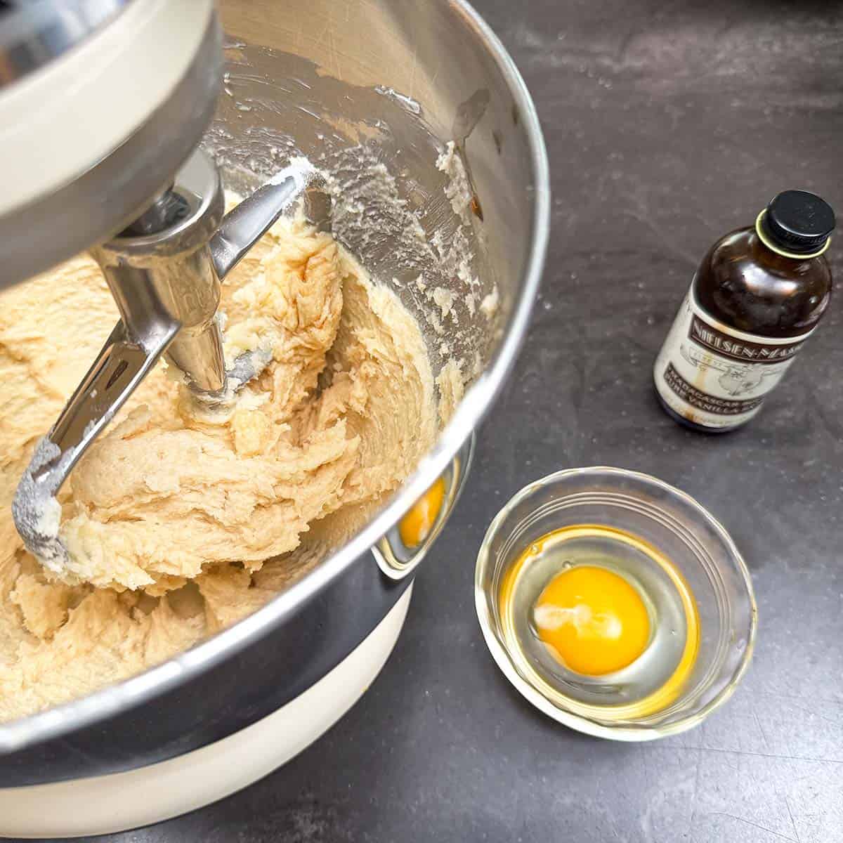Adding vanilla extract and an egg to butter-sugar mixture.
