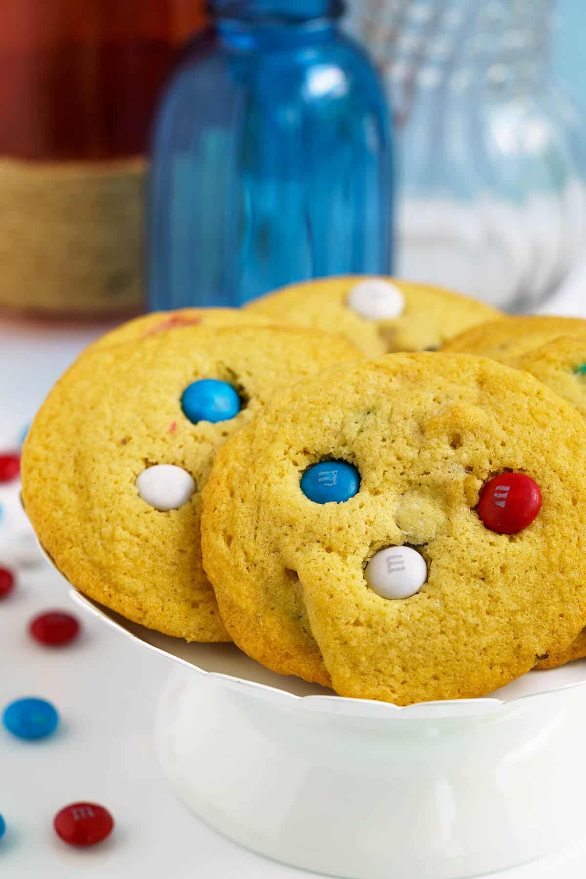Red white and blue MM cookies on a white stand with colored MMs skewed around.