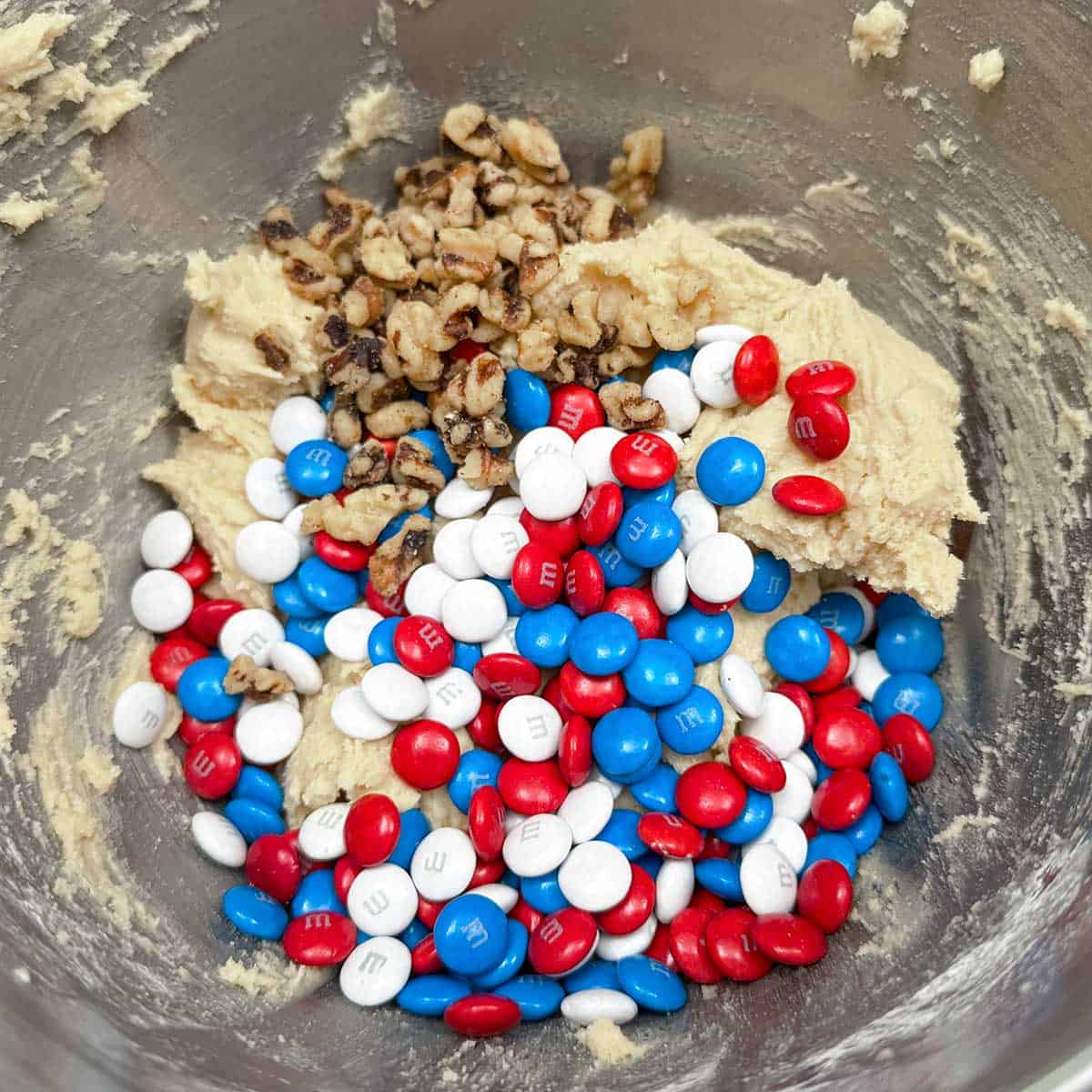 Adding the red white and blue MMs and chopped walnuts to the cookie dough.