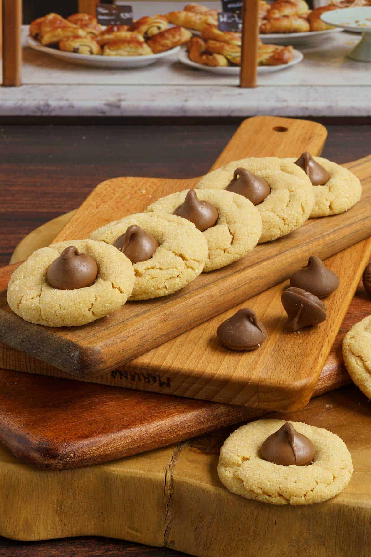 Peanut butter Blossom Cookies lined up on a thin wooden board