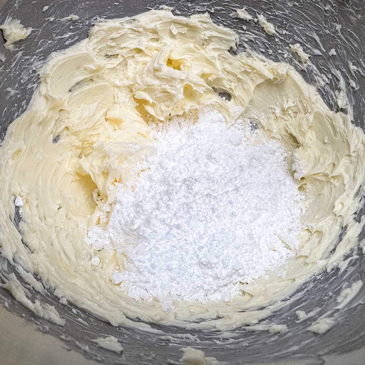 Adding the powdered sugar to the creamed butter and ready to mix for 3 minutes.