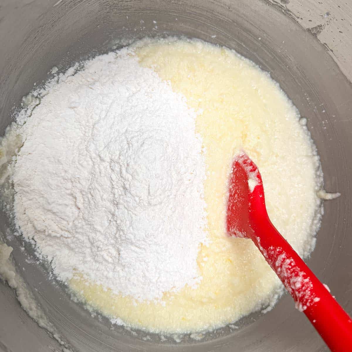 Adding the flour to the wet ingredients and mixing by hand with a spatula.