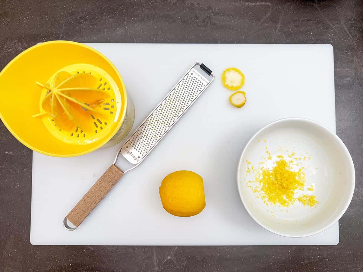 /zesting and juicing lemons for the cookies on a cutting board.