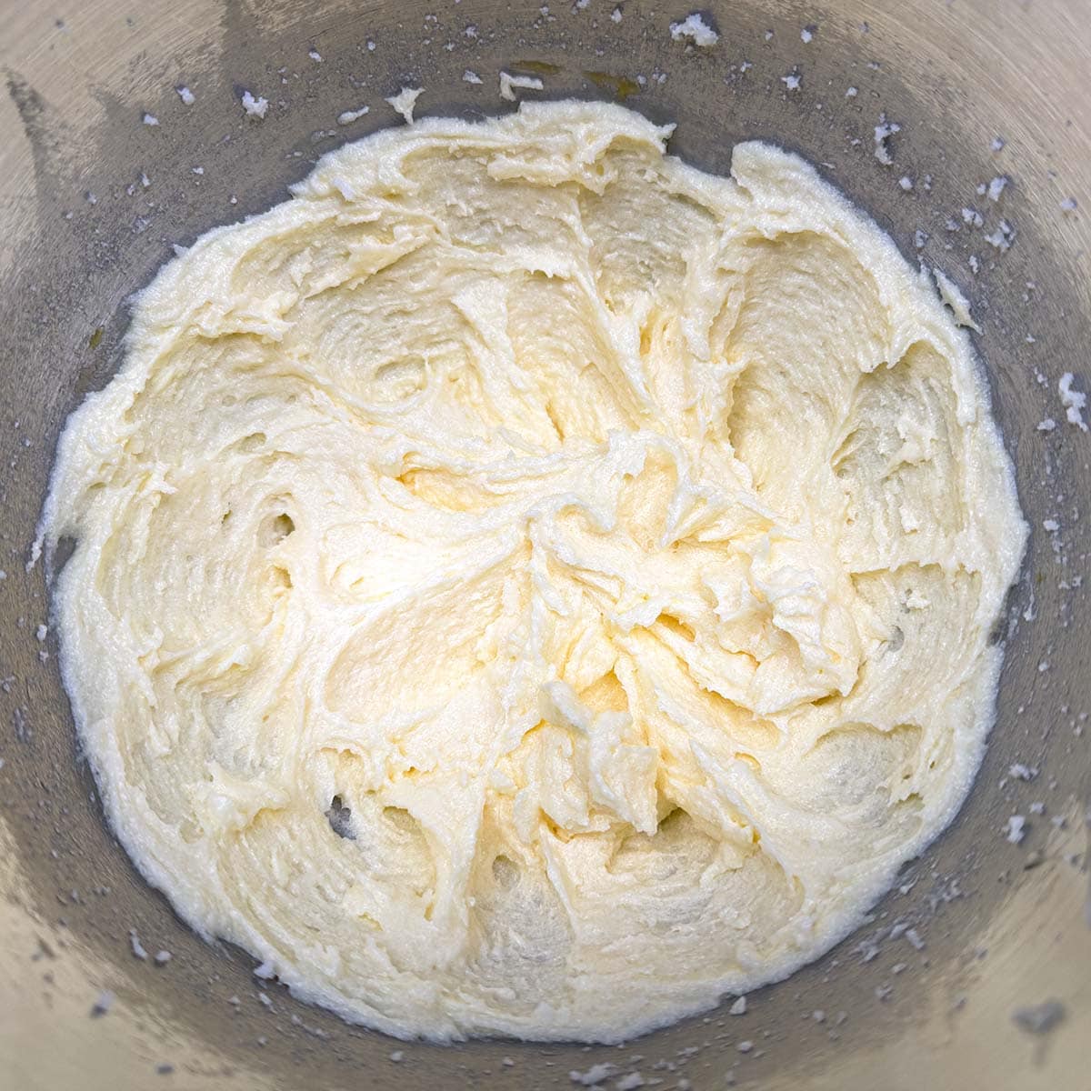 Butter, sugar, and eggs mixed together in a mixer bowl.