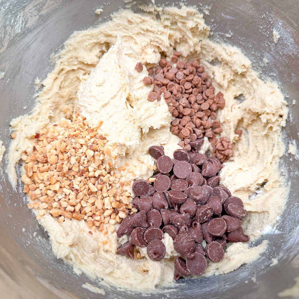 Adding the peanuts, chocolate chips, and caramel chips to the cookie dough.