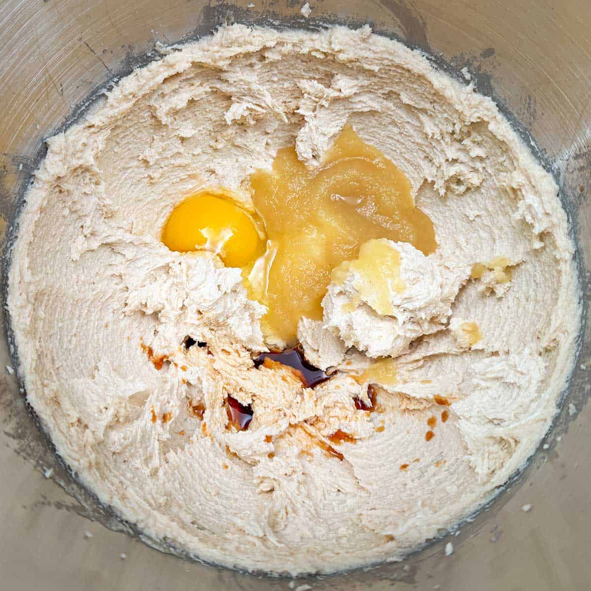 Adding the egg, applesauce, and vanilla extract to the butter-sugar mixture.